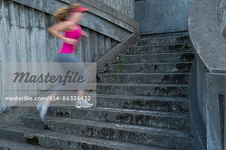 Young woman running up stairs, motion blur