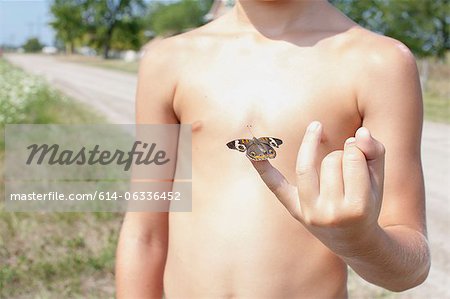 Boy holding butterfly on little finger