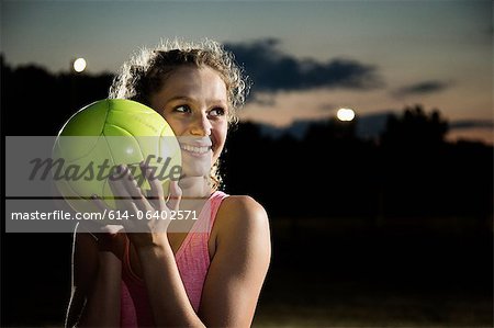 Girl holding soccer ball at night