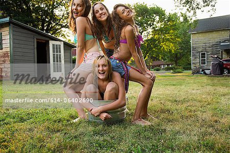 Girl crouching in bucket with friends sitting on her