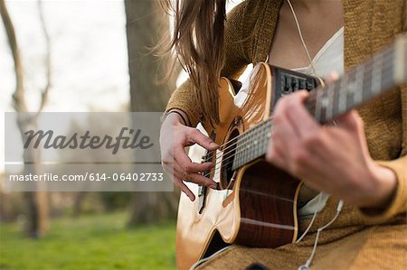 Young woman playing guitar outdoors