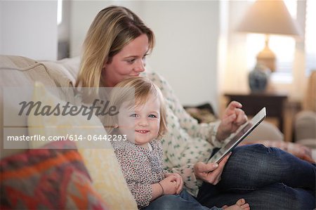 Mother and daughter on sofa with digital tablet
