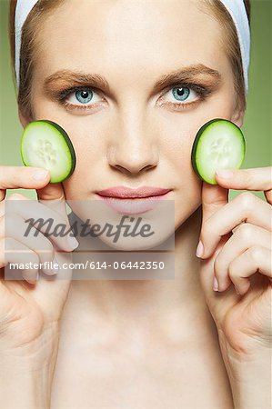 Woman holding two pieces of cucumber