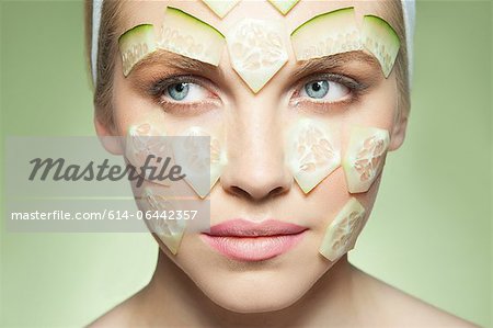 Woman with pieces of cucumber covering face