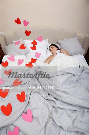 Woman asleep in bed with heart shapes on bedclothes