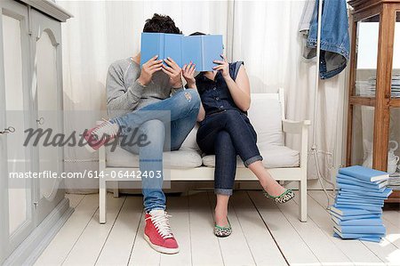 Couple hiding behind books Couple hiding behind books