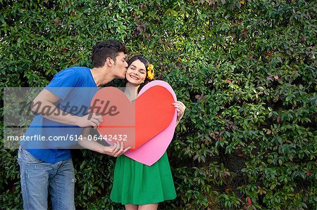 Couple holding heart shape, man kissing woman