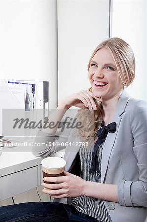 Happy young woman in office with coffee