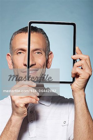 Man covering half his face with digital tablet