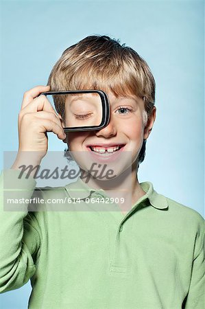 Boy holding smartphone over eye