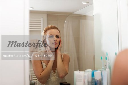 Young woman looking in bathroom mirror