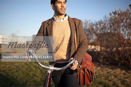 Man with cell phone pushing bicycle Man with cell phone pushing bicycle