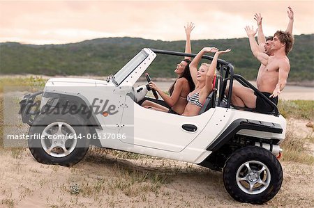 Friends driving jeep on sand dune