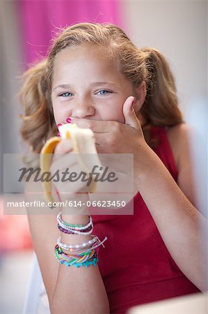 Smiling girl eating banana