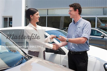 Woman buying new car from salesman