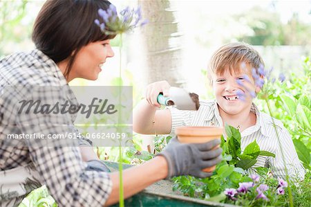 Mother and son potting plants outdoors