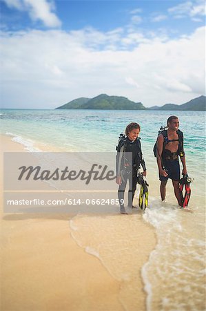 Scuba divers walking on tropical beach