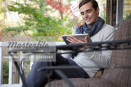 Man using tablet computer on porch