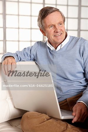 Older man using laptop on sofa