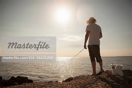 Man fishing in still ocean