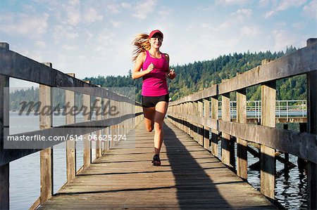 Teenage girl running on wooden dock