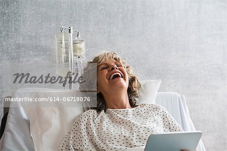 Female hospital patient with digital tablet, laughing