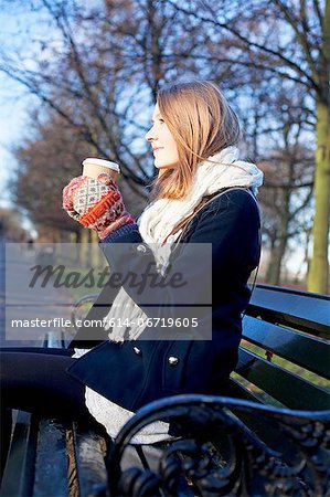 Woman having coffee on park bench