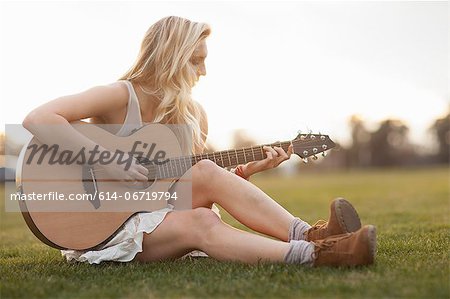 Woman playing guitar in grass
