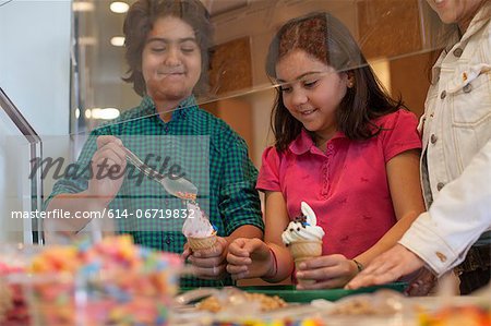 Children putting toppings on yogurt