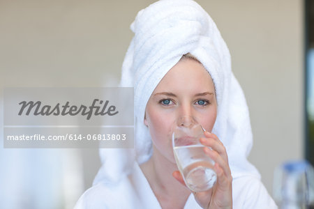 Young woman wearing towel on head drinking water