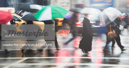 Line of people crossing city street in rain