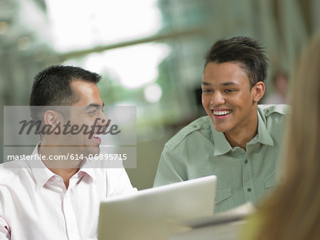 Young student looking at laptop with mid adult tutor, smiling