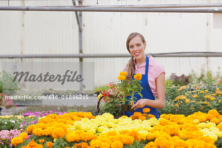 Mid adult woman carrying flowers in garden centre, smiling