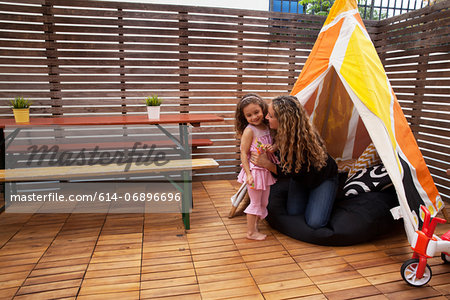 Mother and daughter by tent on patio