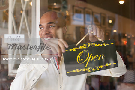 Shopkeeper turning open sign on vintage shop door Shopkeeper turning open sign on vintage shop door