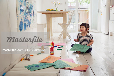 Female toddler sitting on floor with drawings Female toddler sitting on floor with drawings