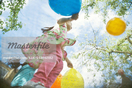 Young girls bouncing on garden trampoline with balloons