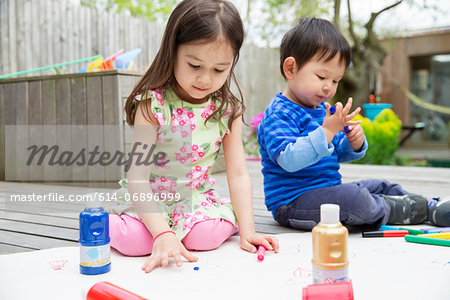 Young brother and sister painting and drawing in garden