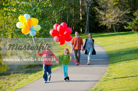 Family walking through park with bunches of balloons