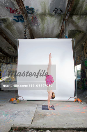Female acrobat practicing handstand in old industrial interior