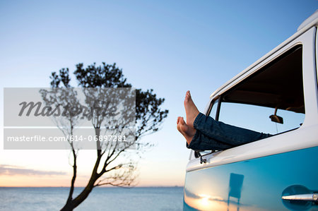 Feet out of camper van window at dusk