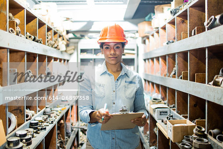 Young woman in warehouse with clipboard Young woman in warehouse with clipboard
