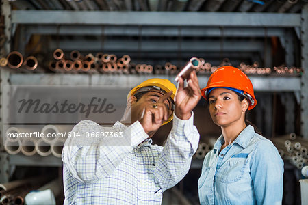 Two warehouse workers looking at copper pipe Two warehouse workers looking at copper pipe