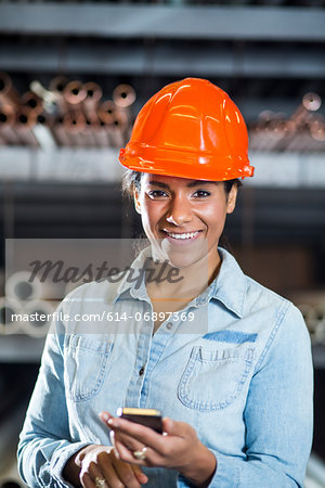 Woman in warehouse holding smartphone Woman in warehouse holding smartphone