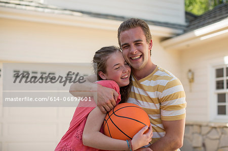 Brother with arm around sister holding basketball