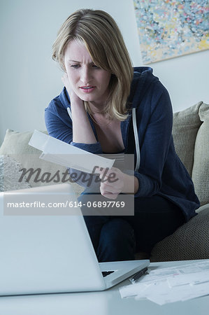 Worried young woman holding bills