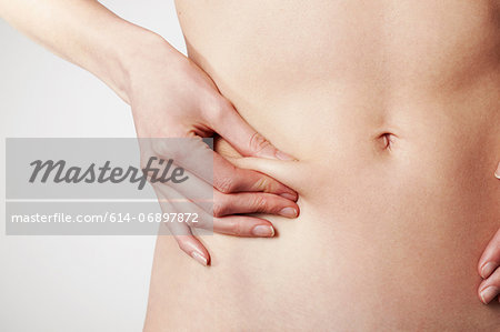 Young woman pinching body fat on stomach