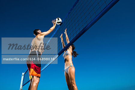 Two beach volleyball players blocking at net