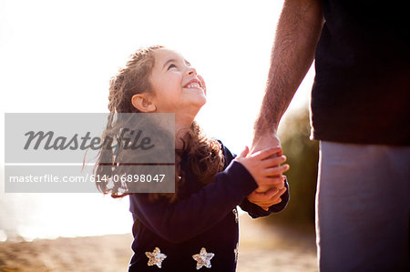 Girl holding father's hand, looking up