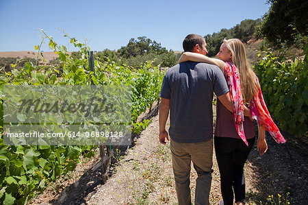Young couple on path in vineyard, woman with arm around man